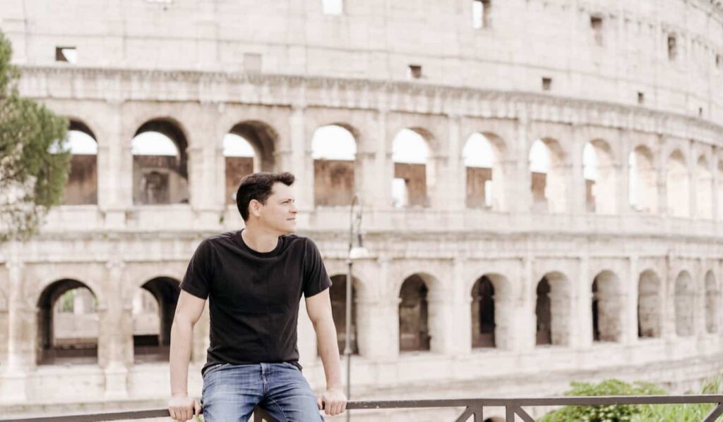 Nomadic Matt sitting by the Colosseum in Rome, Italy