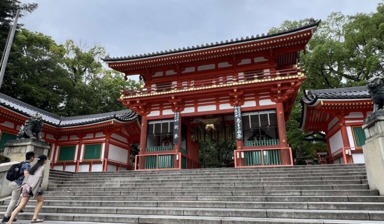 Two young students walking up the steps to the red Yasaka Shrine in Kyoto, Japan